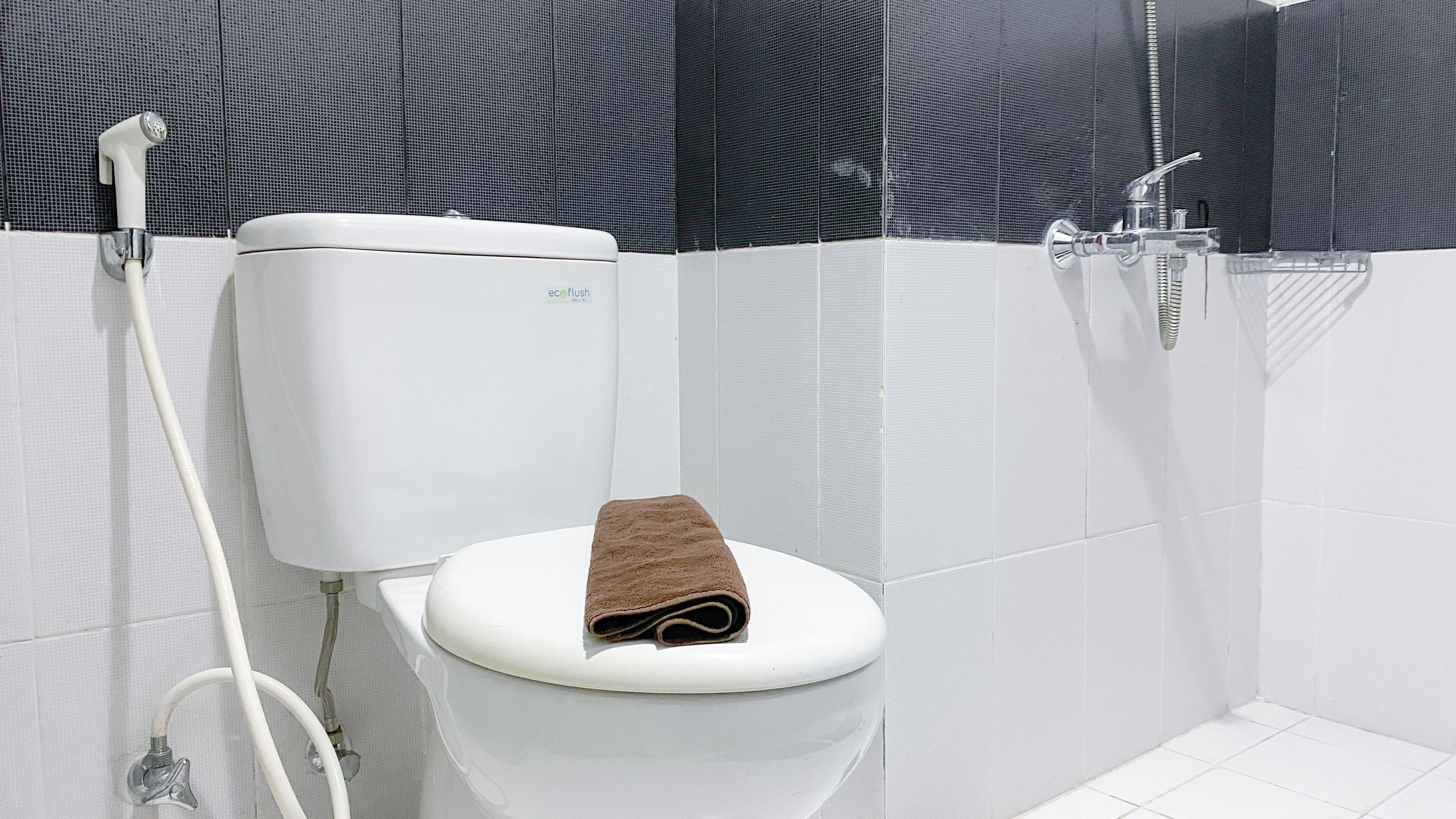 Un baño moderno con inodoro blanco, ducha y soporte para papel higiénico.