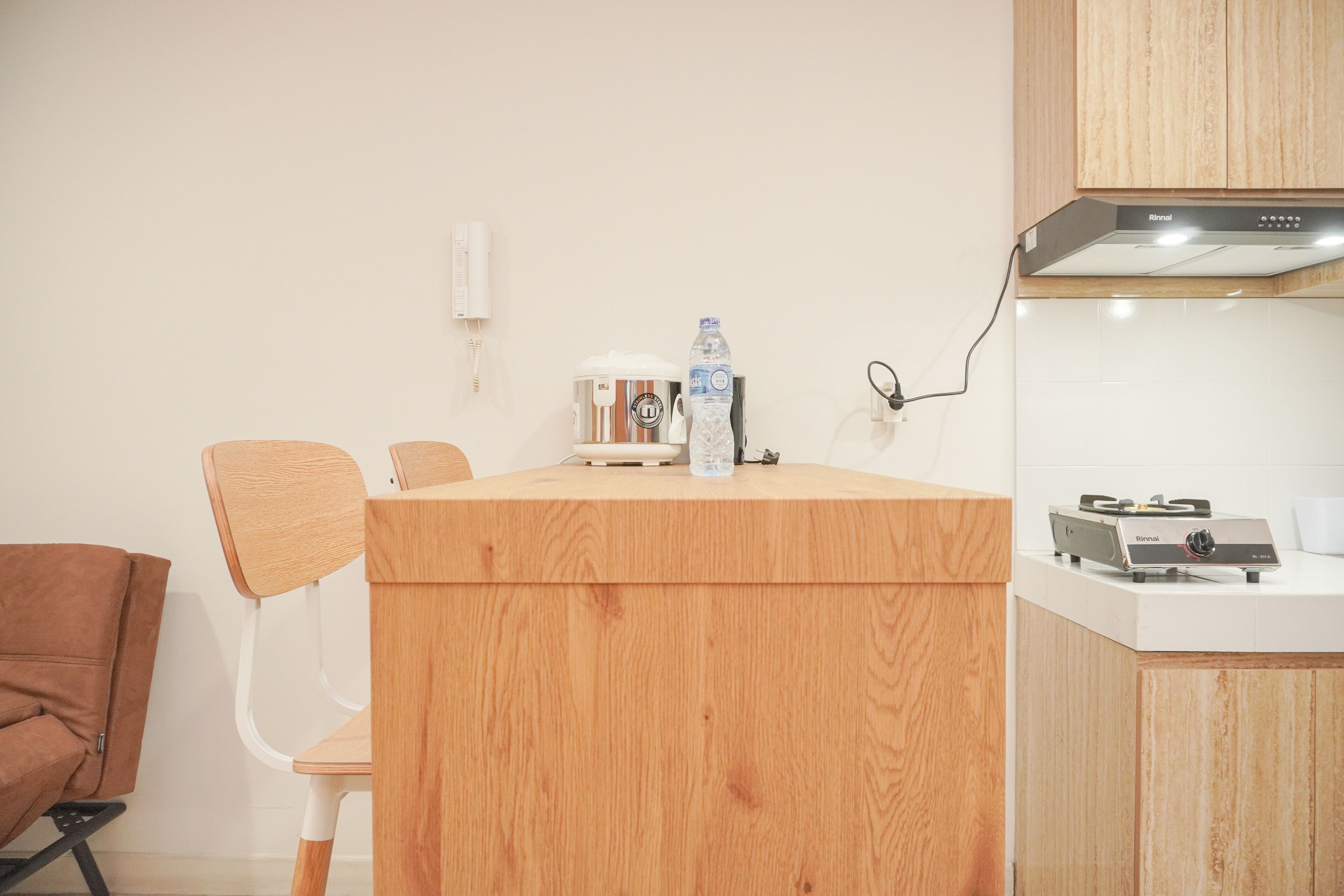 Cocina compacta con encimera de madera, hervidor, botella de agua y estufa.
