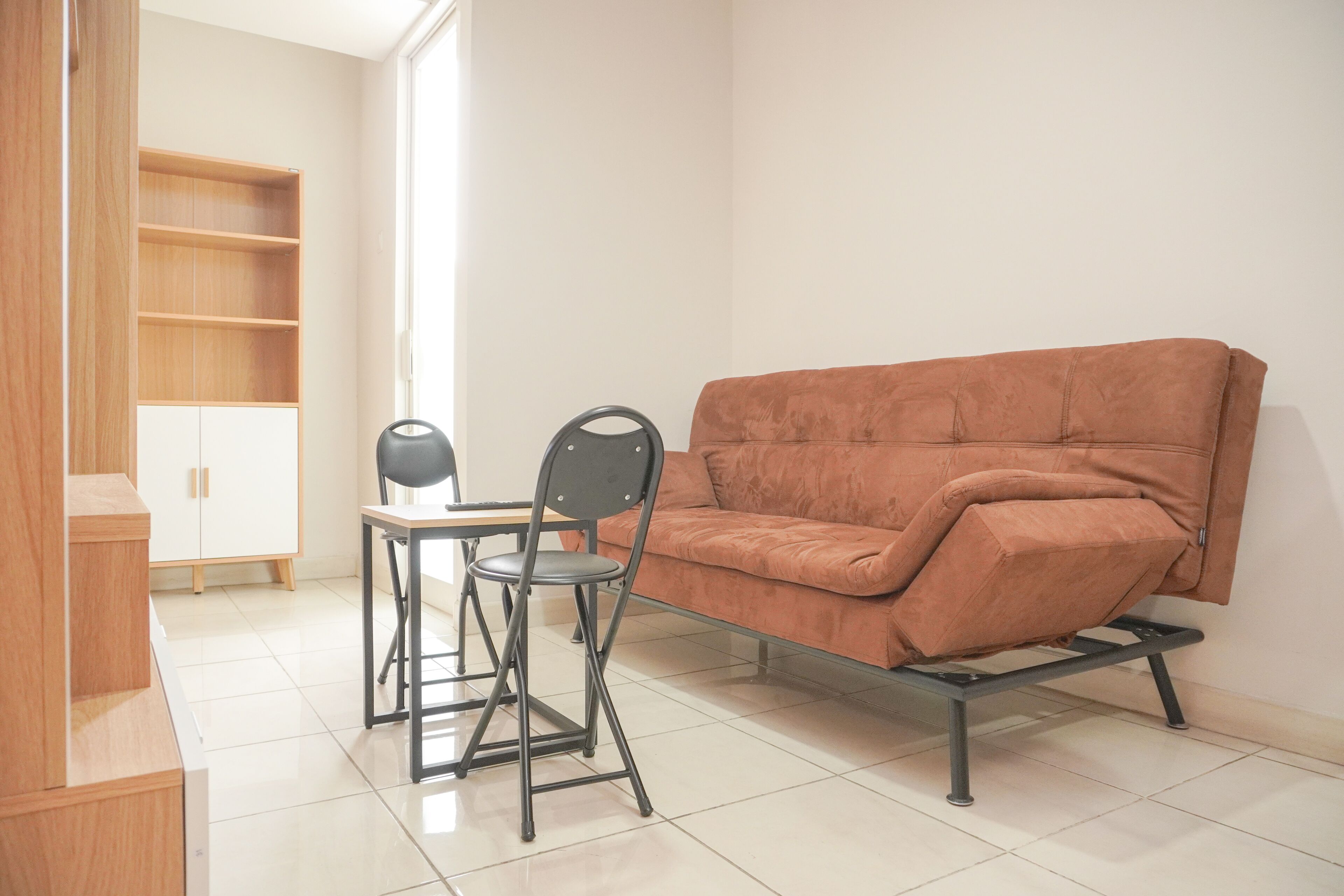 Ein Zimmer mit einer Couch, einem kleinen Tisch, einem Stuhl und einem Schrank.