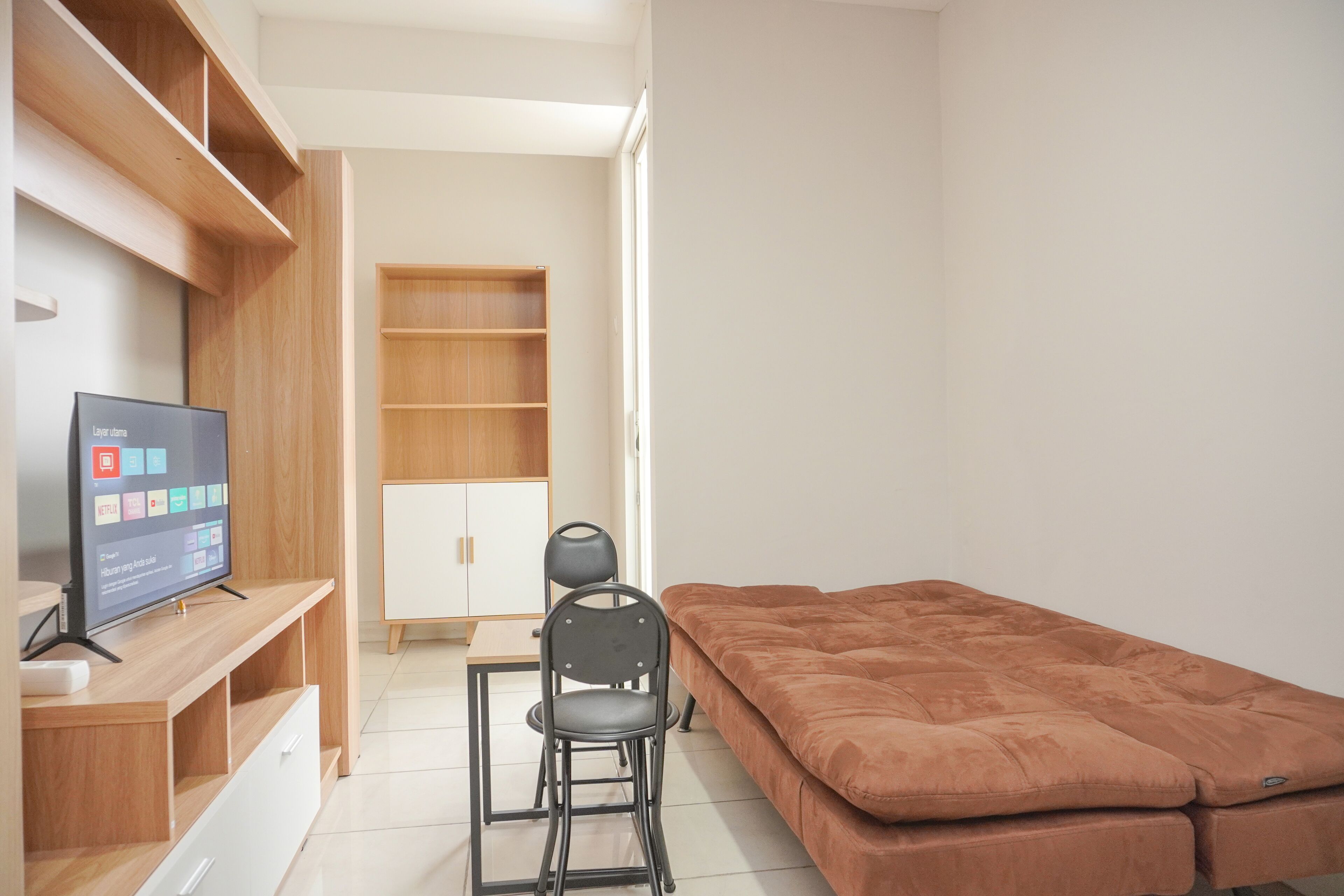 A bedroom with a bed, a desk with a chair, a TV, and a wardrobe.