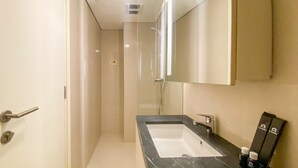 A bathroom with a black marble sink, a mirror, and a shower area. - Minimalist Studio Room Marquis De Lafayette Apartment (Semarang)