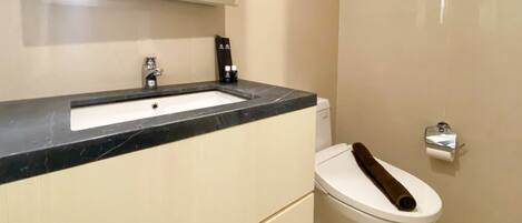 A bathroom with a sink, toilet, and mirror.
