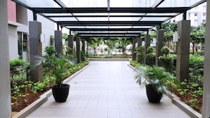 A covered walkway with potted plants on either side, leading to a building entrance. - Warm And Cozy Stay Studio Green Bay Pluit Apartment (Jakarta)