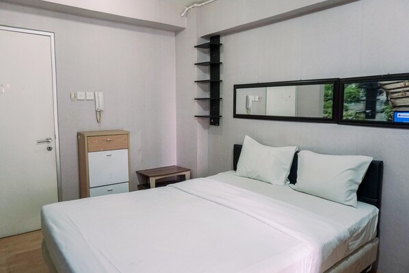 Une chambre à coucher comprenant un lit, une table de chevet, une commode, un miroir et une étagère fixée au mur.