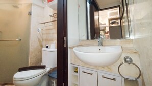 A bathroom with a toilet, sink, and mirror. - Best Location 1Br Without Living Room Apartment Braga City Walk (Bandung)