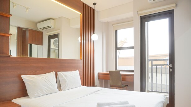 Une chambre d’hôtel avec un grand lit, un bureau, une chaise et une fenêtre donnant sur l’extérieur.