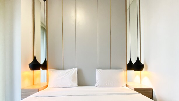 A neatly made bed with white linens and two pillows, flanked by black pendant lamps on either side. - Elegant And Comfort 1Br Sudirman Suites Apartment (Jakarta)