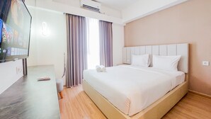 A modern hotel room with a large bed, a flat-screen TV, and a wooden floor. - Homey And Spacious 3Br Sky House Bsd Apartment (Pagedangan)