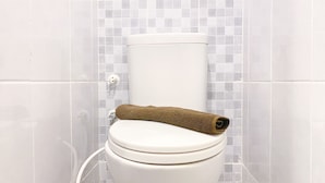 A toilet with a brown towel on top, set against a tiled wall. - Good Choice And Cozy Studio At Tokyo Riverside Pik 2 Apartment (Teluknaga)