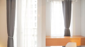 A room with a wooden desk, a white chair, and grey curtains. - Good Choice And Cozy Studio At Tokyo Riverside Pik 2 Apartment (Teluknaga)
