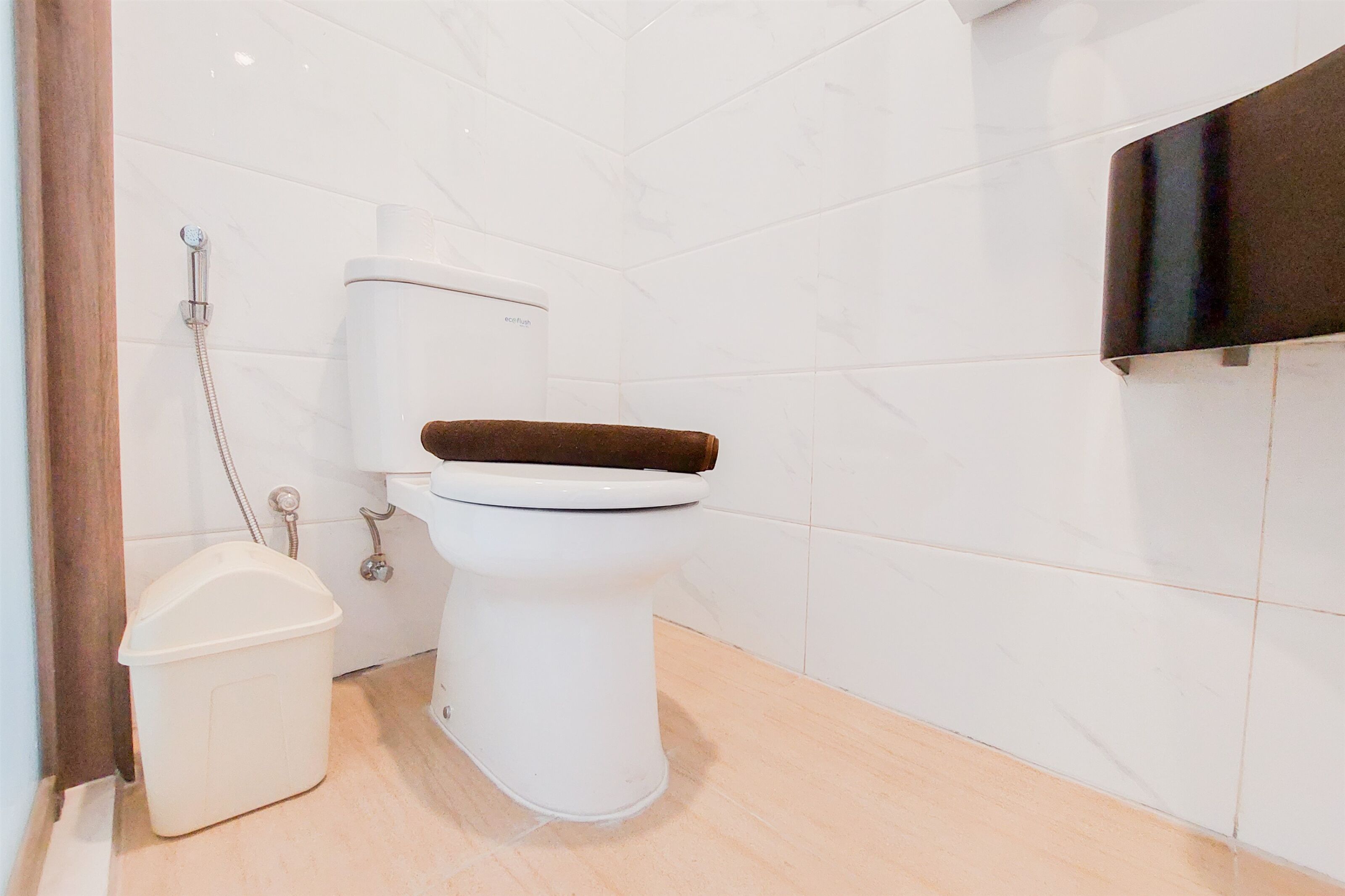 A bathroom with a white toilet, a shower, and a trash bin.