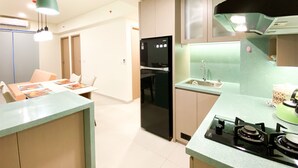 Une cuisine moderne avec un réfrigérateur noir, une cuisinière à gaz et un évier. On y trouve également un coin repas avec une table et des chaises.