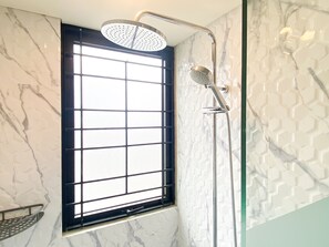 Shower area features a large window, chrome showerhead, and handheld attachment.