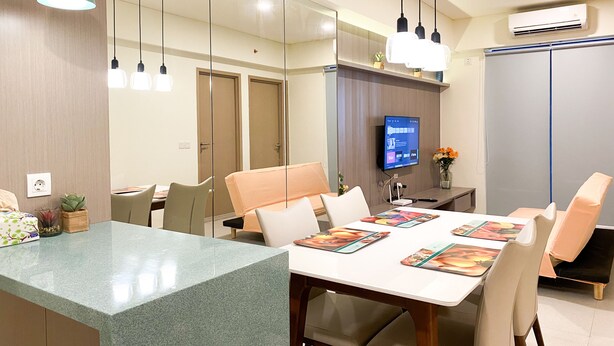 Une chambre d’hôtel moderne dotée d’un coin repas, d’un téléviseur à écran plat et d’un grand miroir.