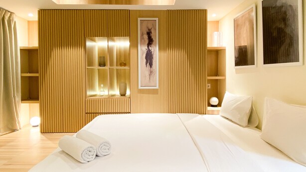 Ein modernes Hotelzimmer mit einem großen Bett, Holzvertäfelung und Kunstwerken an den Wänden.