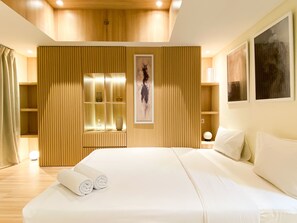 Une chambre d’hôtel moderne avec un grand lit, des panneaux de bois et des œuvres d’art accrochées aux murs.
