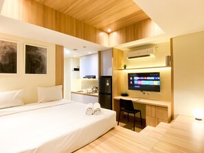 Relax in a spacious room with a large bed, desk area, and kitchen.