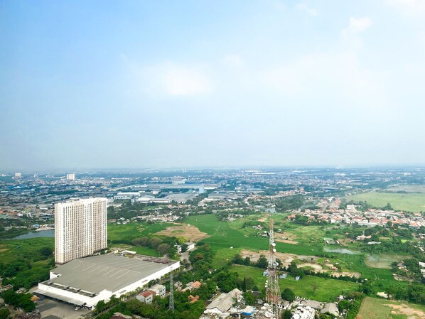 Surrounded by green fields and urban structures, this high-rise building offers a unique blend of city and nature views.