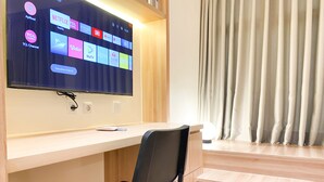 Ein modernes Zimmer mit einem an einer Holzwand montierten Flachbildfernseher, einem schwarzen Bürostuhl und einer Treppe, die zu einer oberen Ebene führt.