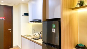 Eine moderne Küche mit weißen Schränken, einem schwarzen Kühlschrank und einer Holzausziehtheke.