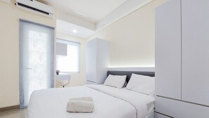 A modern hotel room with a large bed, a wardrobe, and a window with blinds. - Good Deal And Homey Studio Apartment At B Residence (Pagedangan)
