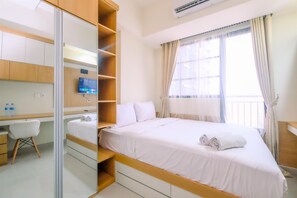 A bedroom with a bed, a desk, and a chair. There is a window with curtains and an air conditioning unit on the wall.