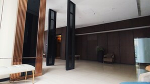 A modern lobby with a white bench, dark wooden panels, and a glass partition.
