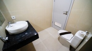 Ein kleines Badezimmer mit einem weißen Waschbecken, einer Toilette und einer Tür.