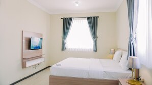Una camera d'albergo con un letto, una TV a parete, una lampada da comodino e tende.