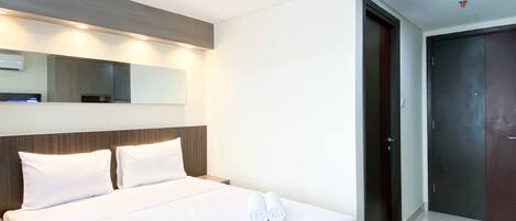 A hotel room with a large bed, a nightstand, a mirror, and a door.