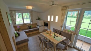 A modern, open-plan living and dining area with a wooden floor, a dining table with chairs, a sofa, and a TV mounted on the wall. - Chalet in Mayrhofen near Penkenbahn Ski Lift (Mayrhofen)
