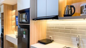 A modern kitchen with a built-in microwave, a kettle, and a stainless steel sink.