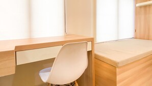 A modern, minimalist room with a wooden desk, a white chair, and a cushioned bench.