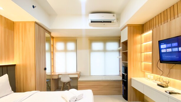 A modern hotel room with a bed, a desk, a TV, and a built-in wardrobe.
