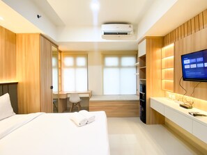 A modern hotel room with a bed, a desk, a TV, and a built-in wardrobe. - Simply Look Studio At 53Th Floor Pollux Chadstone Apartment (Cikarang)