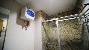 A bathroom with a shower area, a white wall-mounted heater, and a tiled shower enclosure. - Homey 1Br Apartment At Aryaduta Residence Surabaya (Surabaya)