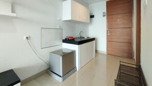 A compact kitchen with a built-in oven, a sink, and white cabinets. - Nice And Comfy 1Br At Dago Suites Apartment (Bandung)