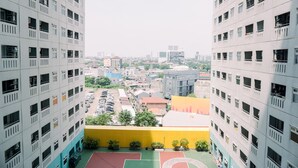 A high-rise building with multiple balconies and a basketball court at the ground level. - Good Deal And Nice Studio Green Pramuka City Apartment (Jakarta)