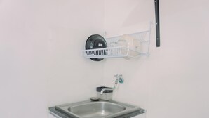 A kitchen with a stainless steel sink, a dish rack, and a wall-mounted faucet. - Good Deal And Nice Studio Green Pramuka City Apartment (Jakarta)