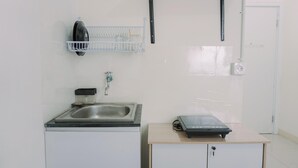 A compact kitchenette with a sink, a small countertop, and a built-in stove. - Good Deal And Nice Studio Green Pramuka City Apartment (Jakarta)