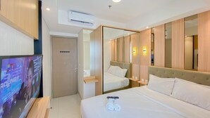 Une chambre d’hôtel moderne équipée d’un lit, d’une télévision, d’une armoire et d’un miroir.