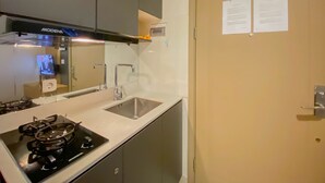 Une cuisine de taille réduite, équipée d’une cuisinière, d’un évier et de placards.