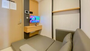 Une chambre d’hôtel moderne équipée d’un lit, d’une télévision, d’un bureau et d’une étagère.