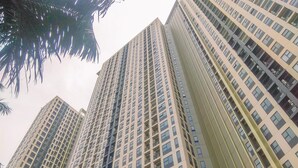 A high-rise building with multiple floors, featuring a grid-like window pattern and balconies.