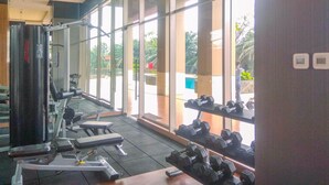 A gym with exercise equipment, large windows, and a view of the outdoors.