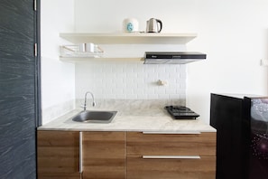 A modern kitchen with a stainless steel sink, a gas stove, and a built-in oven. - Well Furnished And Comfy Studio Collins Boulevard Apartment (Tangerang)