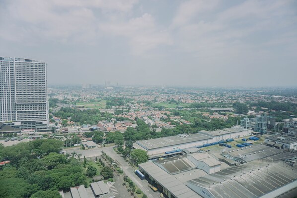 An aerial view of a cityscape with a large industrial building, residential areas, and a prominent high-rise hotel. - Well Furnished And Comfy Studio Collins Boulevard Apartment (Tangerang)