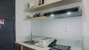 Une cuisine moderne dotée d’un évier en acier inoxydable, d’une hotte de cuisine Rinnai et d’une bouilloire électrique portative posée sur le plan de travail.