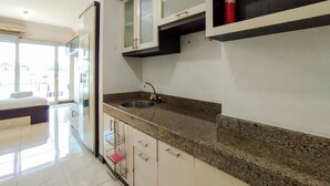 A modern kitchen with a granite countertop, stainless steel sink, and white cabinetry. - Cozy Studio At Galeri Cimbuleuit 1 Apartment (Bandung)
