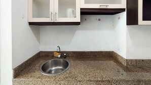 A kitchen with a granite countertop, stainless steel sink, and white cabinets with glass doors. - Cozy Studio At Galeri Cimbuleuit 1 Apartment (Bandung)